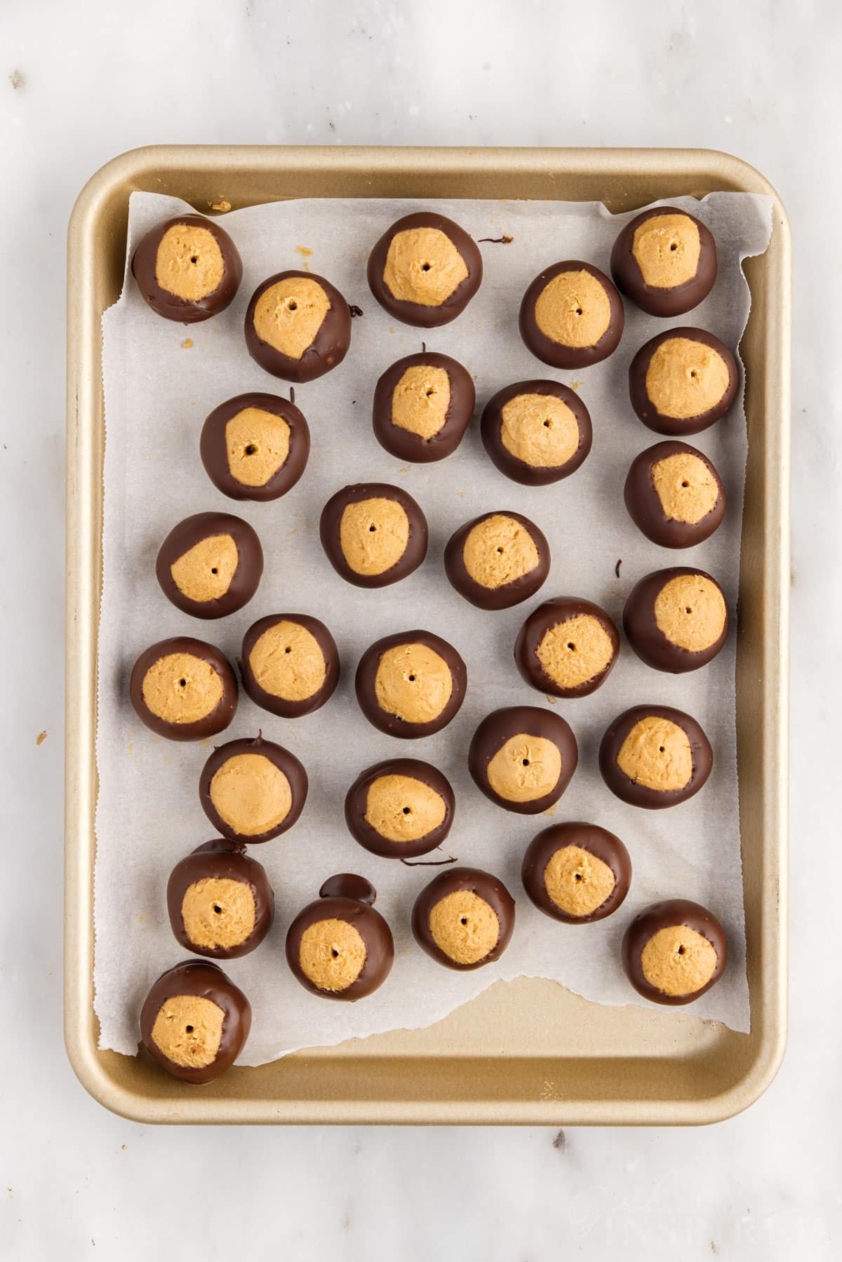 Buckeye Balls on a parchment paper lined cookie sheet.