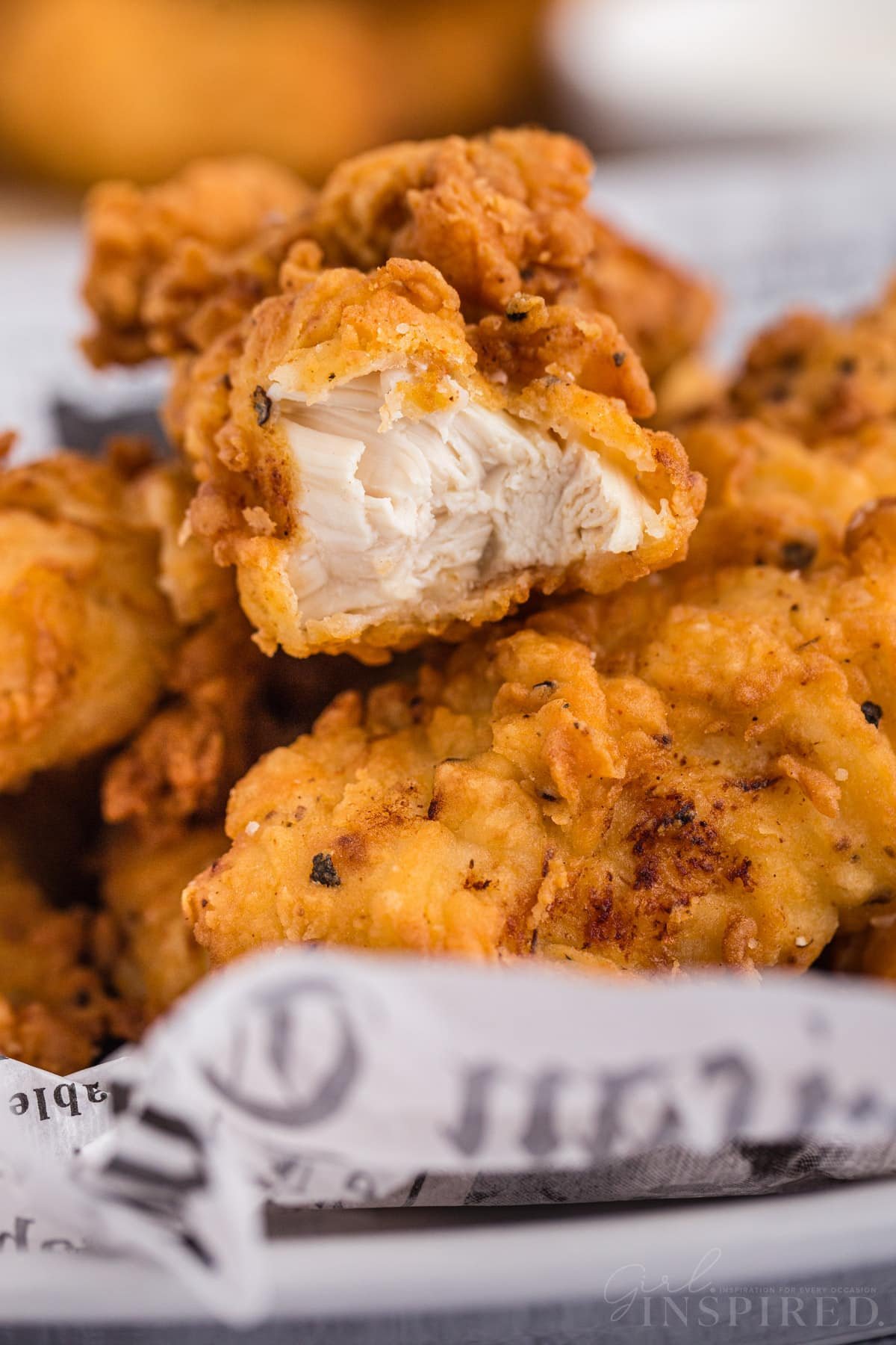 Close up of buttermilk fried chicken tenders with a bite taken from one piece.