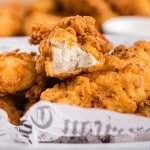 Close up of buttermilk fried chicken tenders on newspaper.