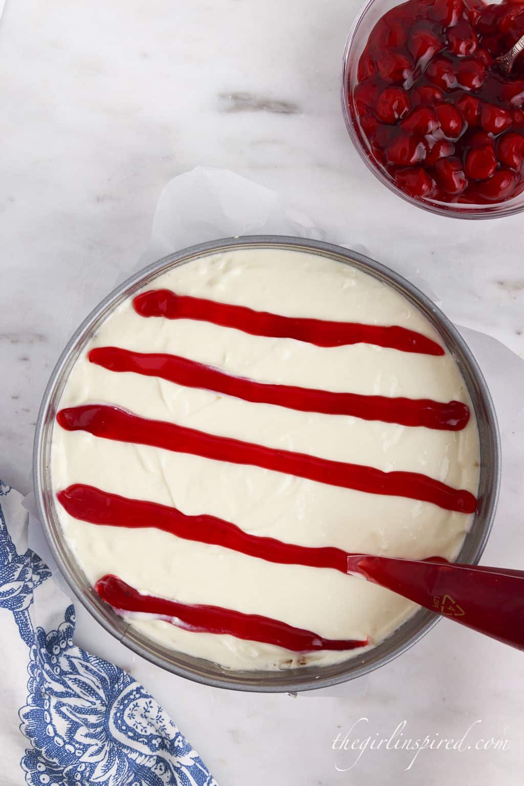 Cheesecake piped with cherry pie filling in stripes.