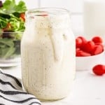 Close up of Hidden Valley Ranch Dressing in a mason jar a salad and tomatoes in the background.