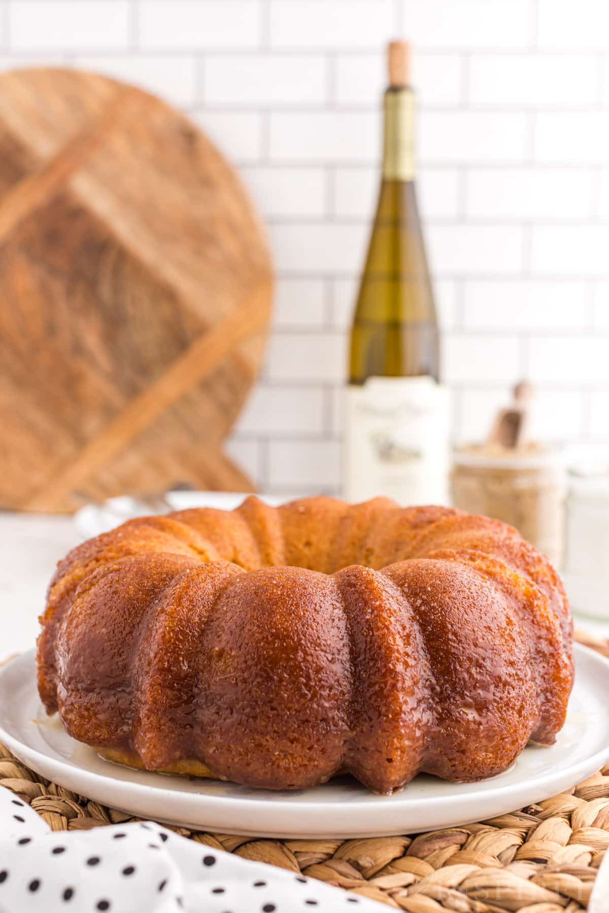 Crack cake on a white cake plate, a bottle of sweet white wine in the background.