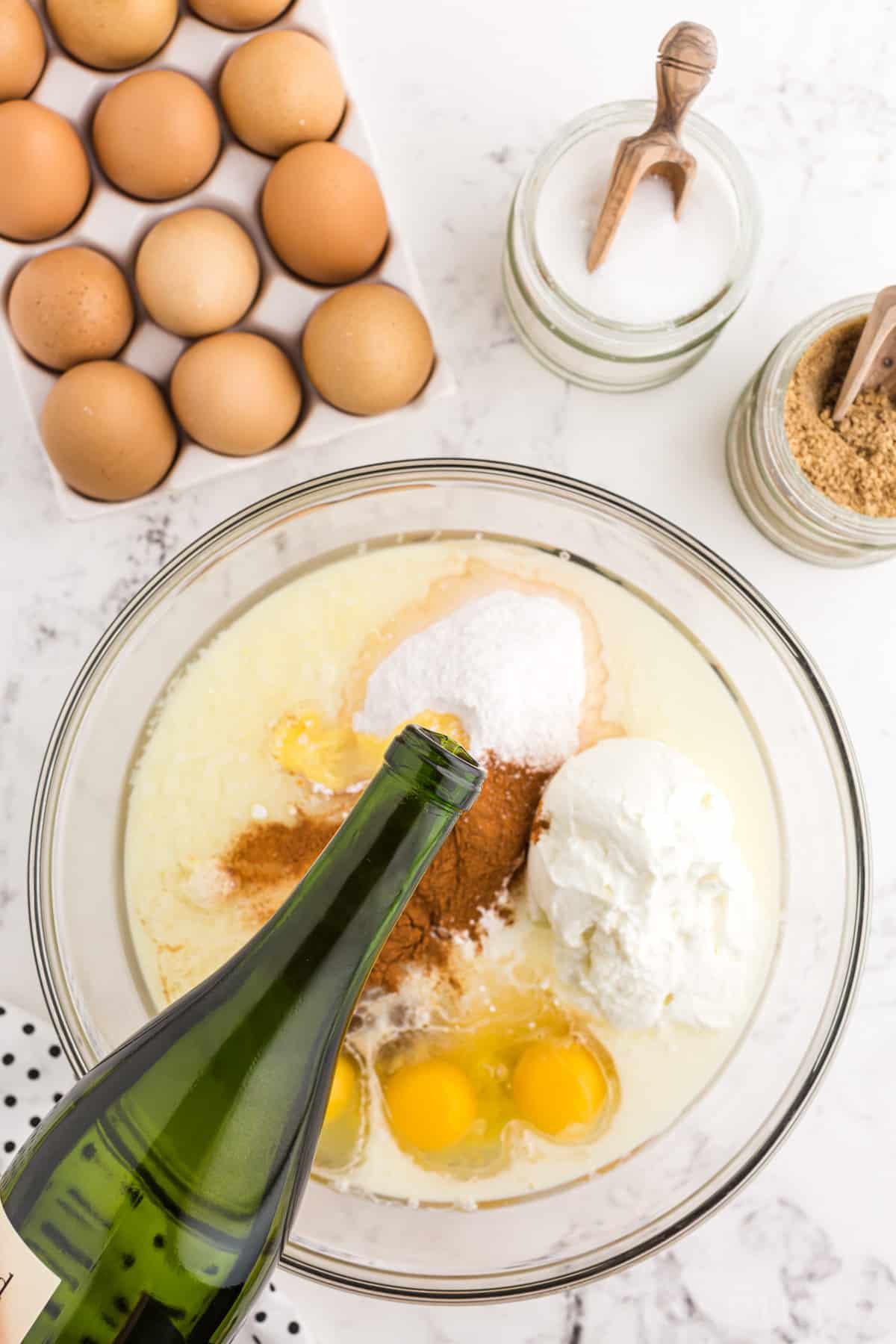 Crack cake batter ingredients in a medium mixing bowl with white wine poured into the mixture, crack cake recipe ingredients place around the mixing bowl.