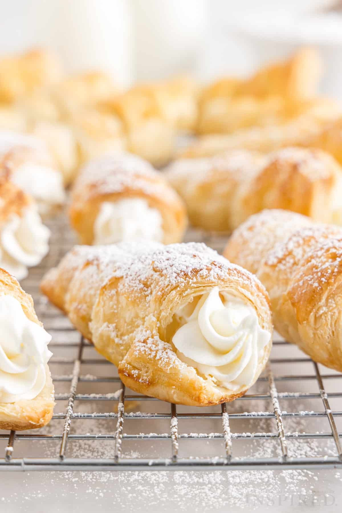 Front view of a cooling rack of Cream Horns dusted with powdered sugar.