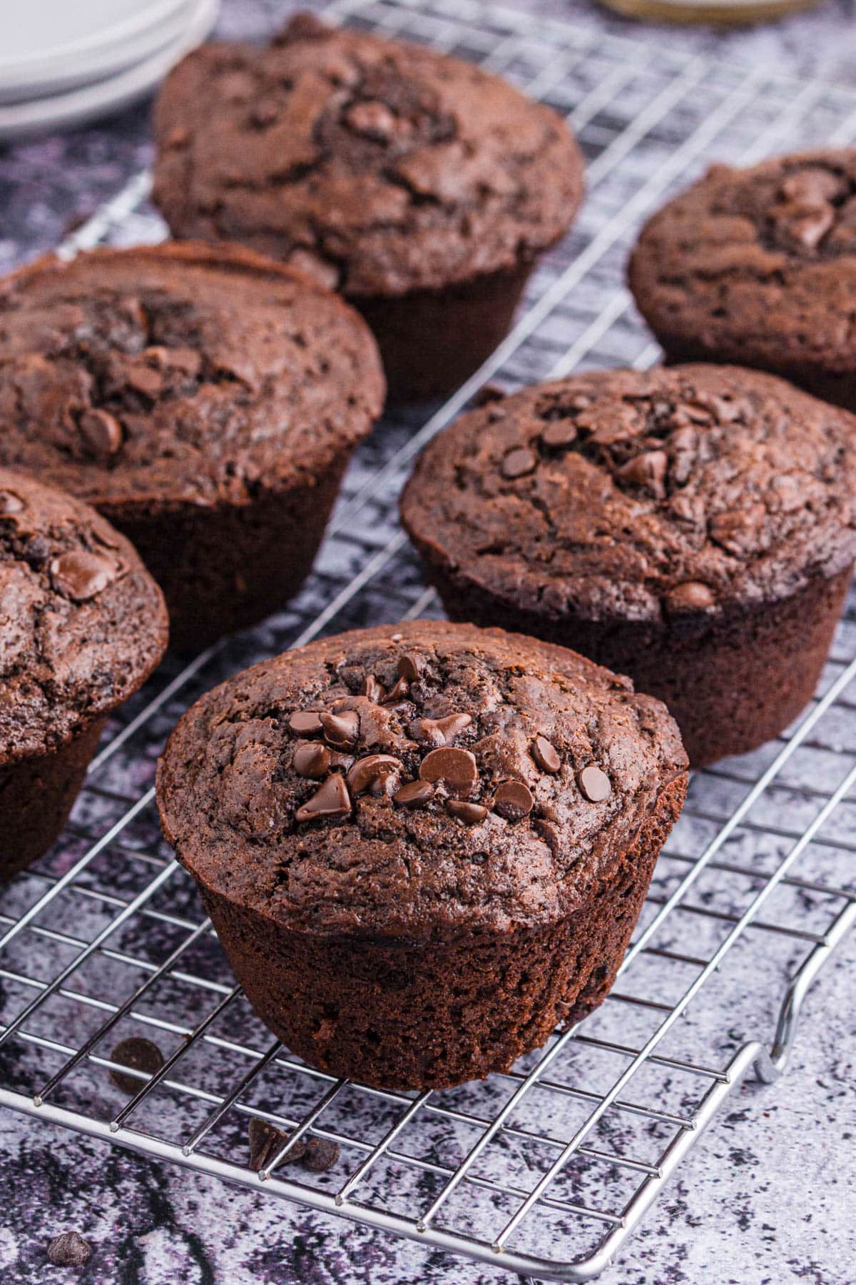 Wire cooling rack with six double chocolate muffins.