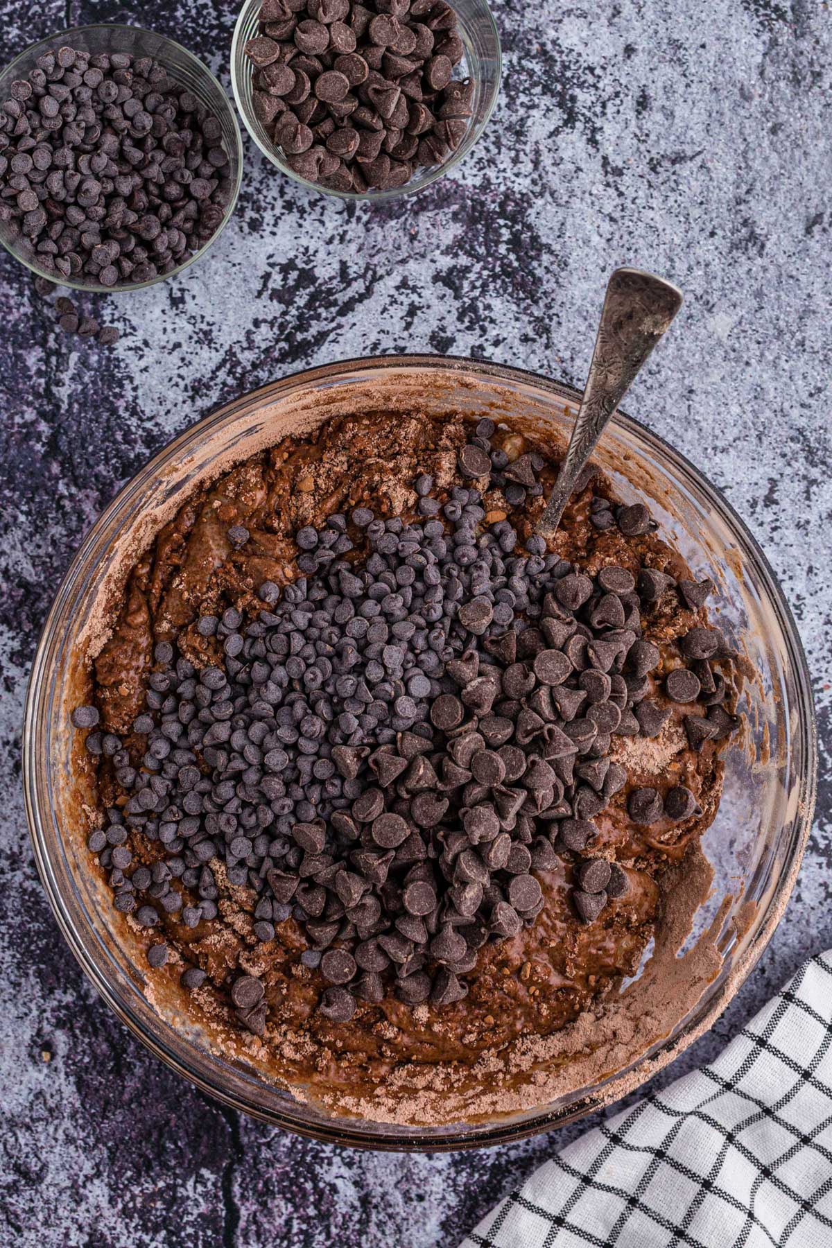 Bowl of double chocolate muffins batter with chocolate chips and metal spoon. 