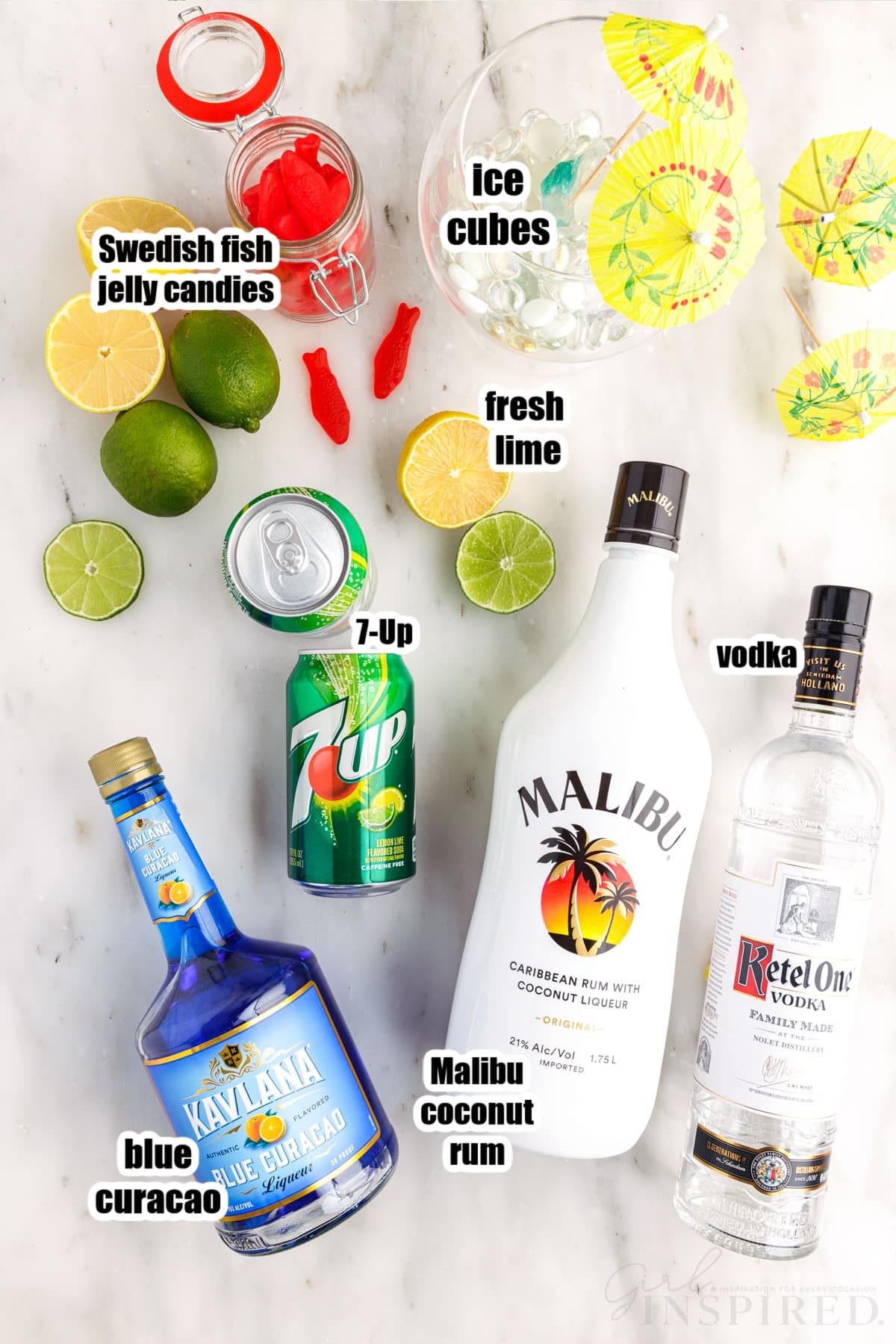 Individual ingredients for fish bowl drink - bottles of liquor, 7-Up, lemonds and limes, and Swedish fish, with text labels.