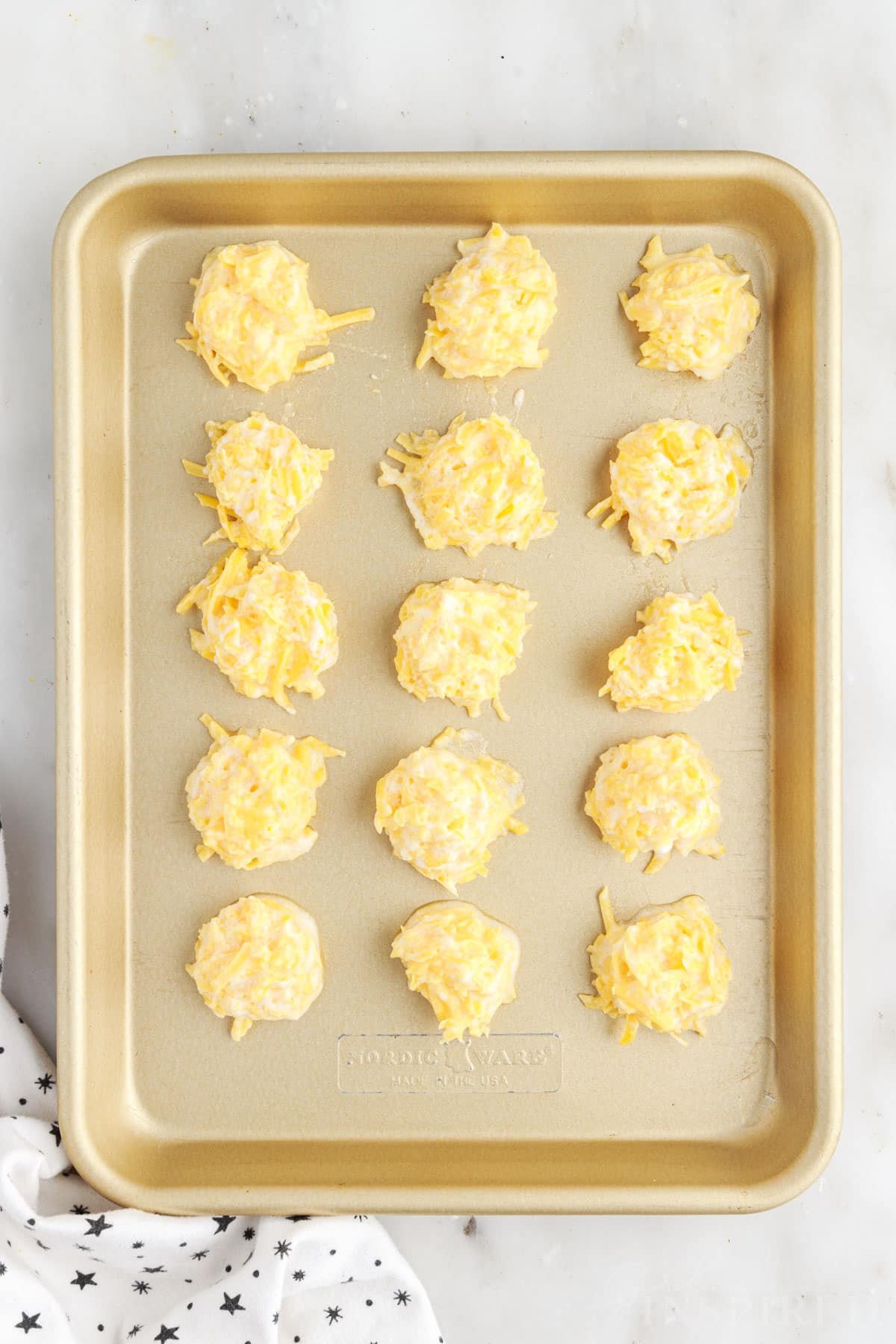 Cookie sheet with 15 Fried Cheese Balls on it before baking.