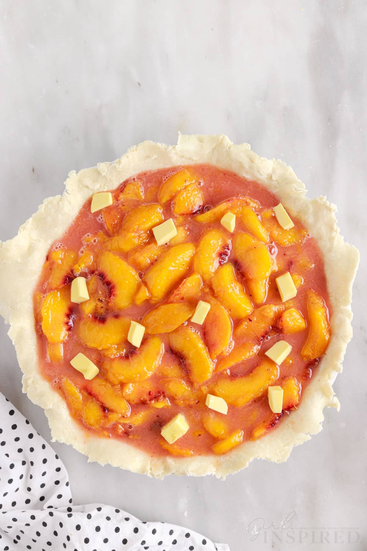 Butter added to sliced peaches in pie crust.