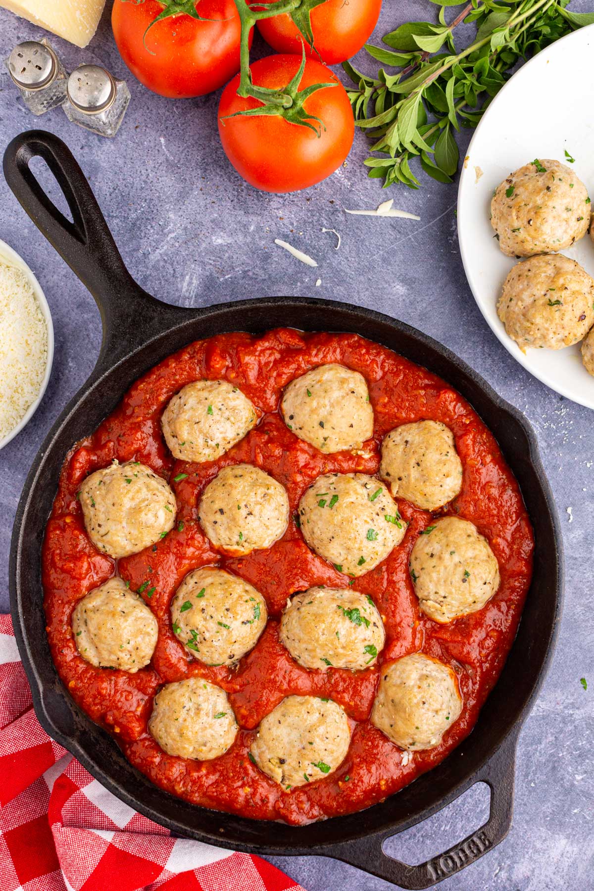 Meatballs nestled into the marinara sauce in a skillet.