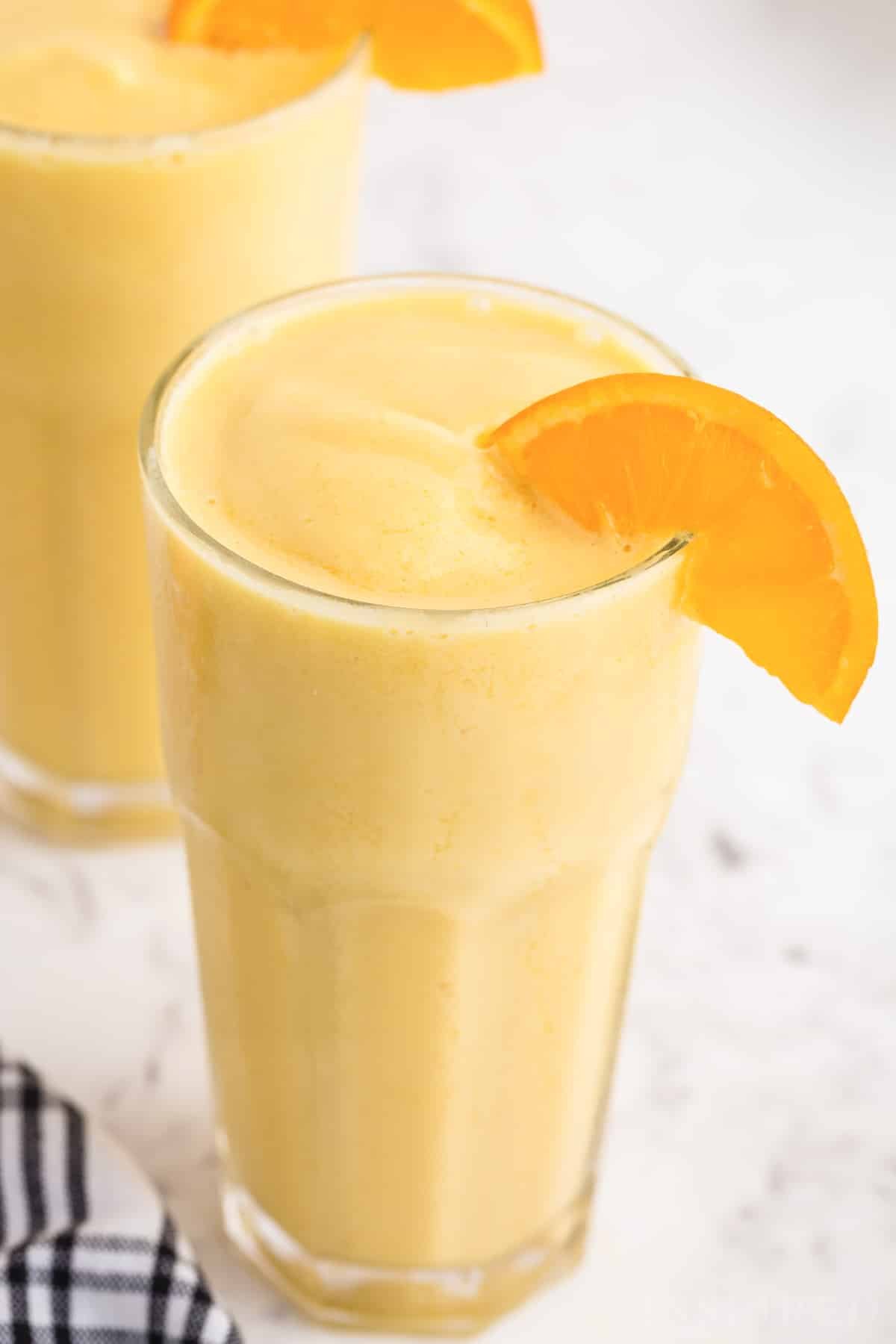 Close up of Orange Julius glasses with orange wedge garnish.