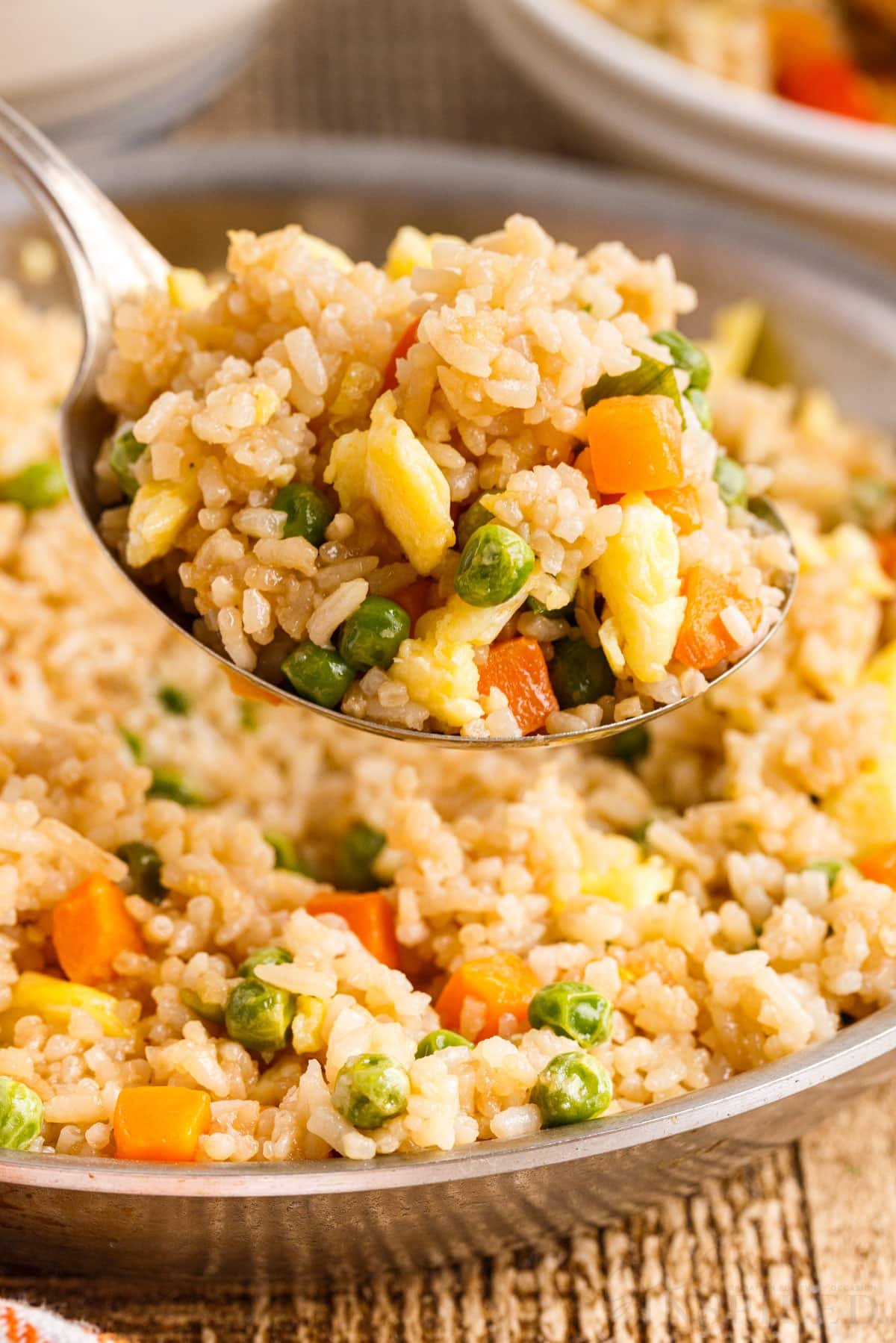 A serving spoon of Panda Express Fried Rice over a pan of it.