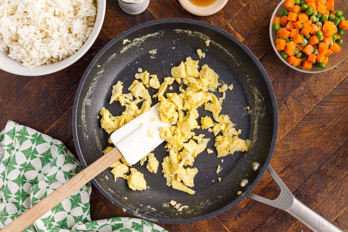 Scrambled eggs in a skillet with a spatula to make Panda Express Fried Rice.