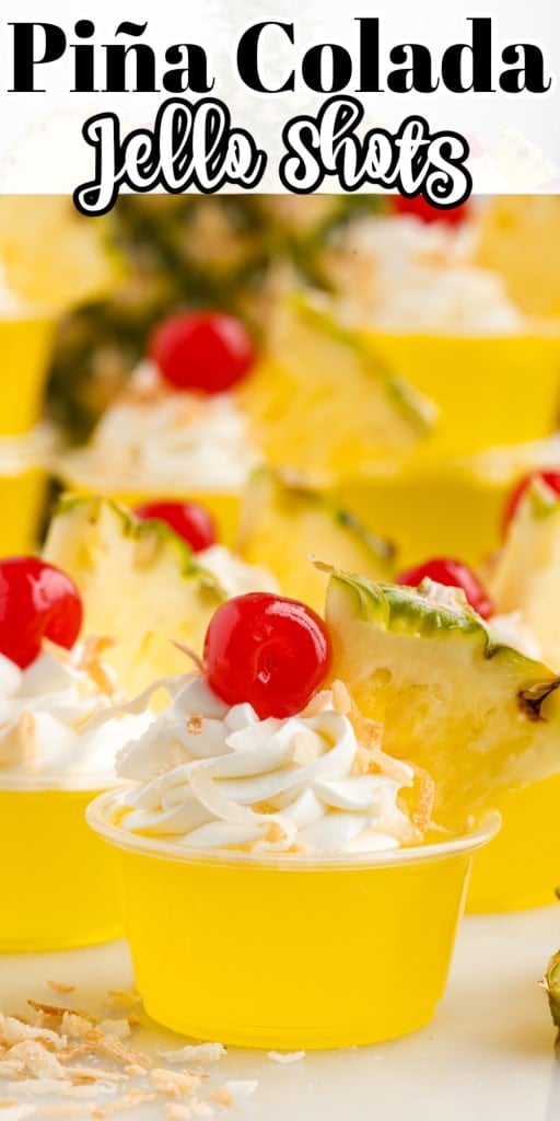 Piña Colada Jello Shots garnished with whipped cream, toasted coconut, cherry, and a slice of pineapple.