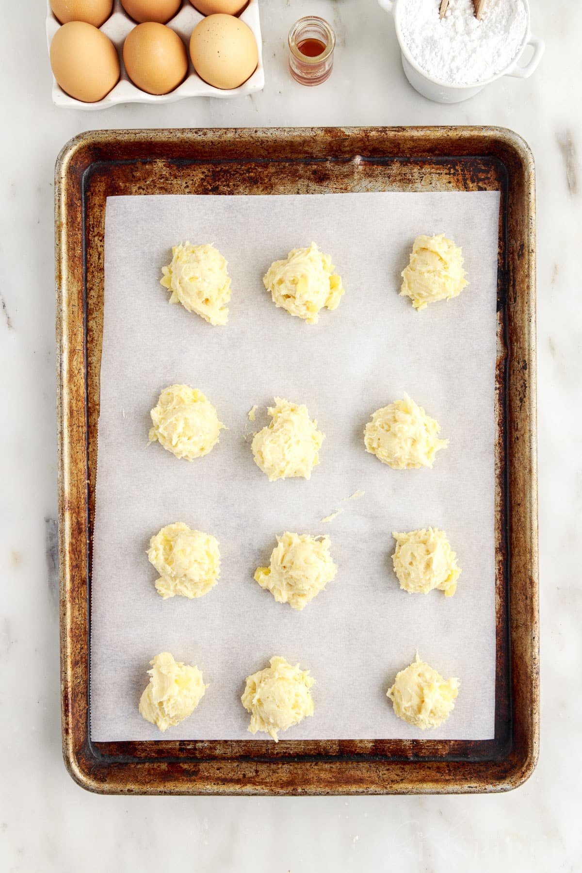 Pineapple Cookie dough balls on parchment paper lined cookie sheet.