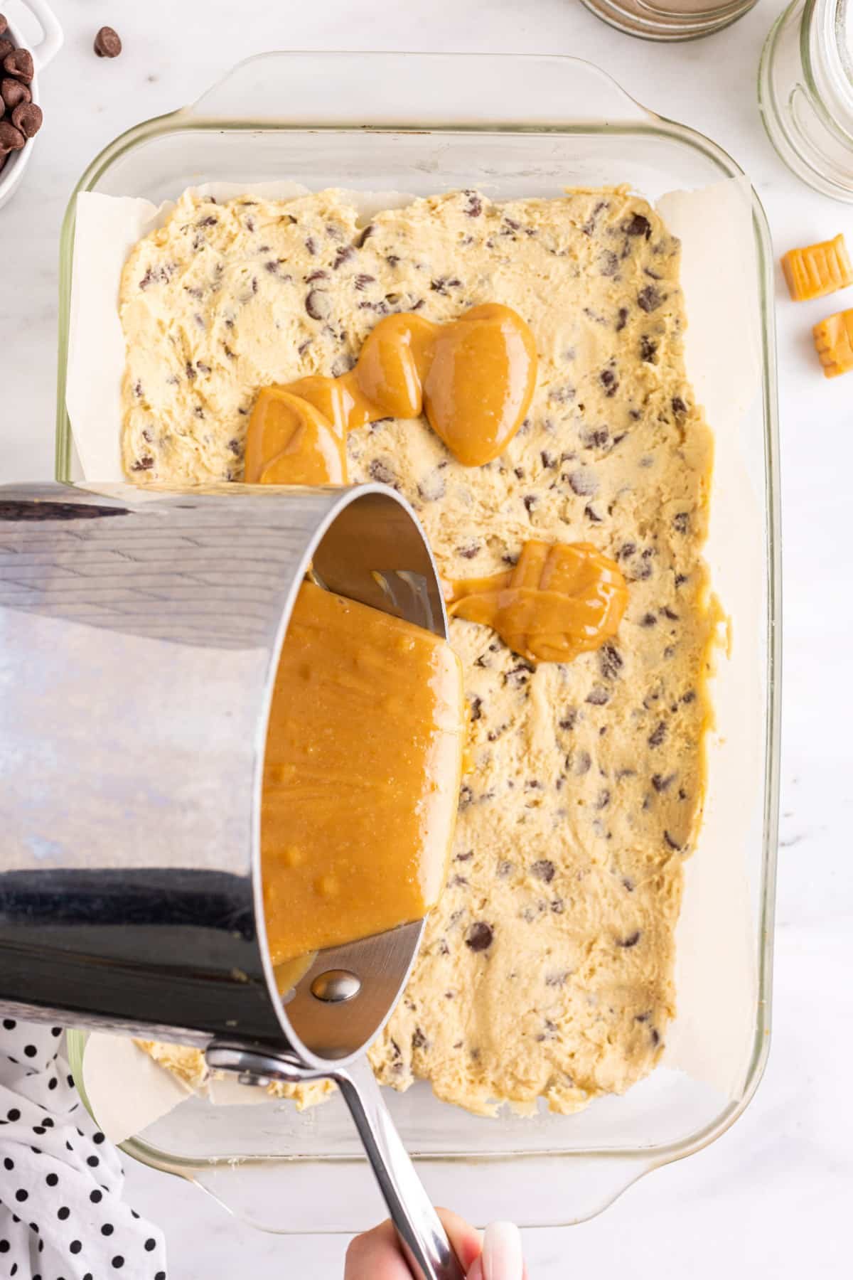 Cookie dough pressed into a baking pan with homemade caramel sauce poured over.