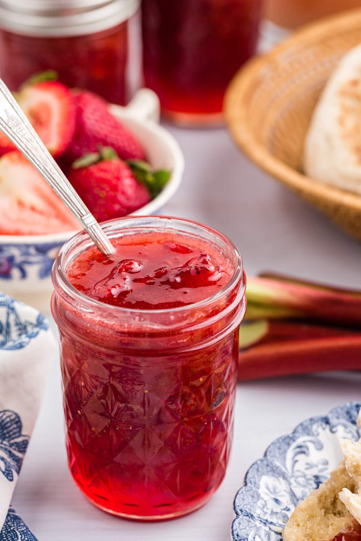 Strawberry rhubarb jam jar with a spoon in it.