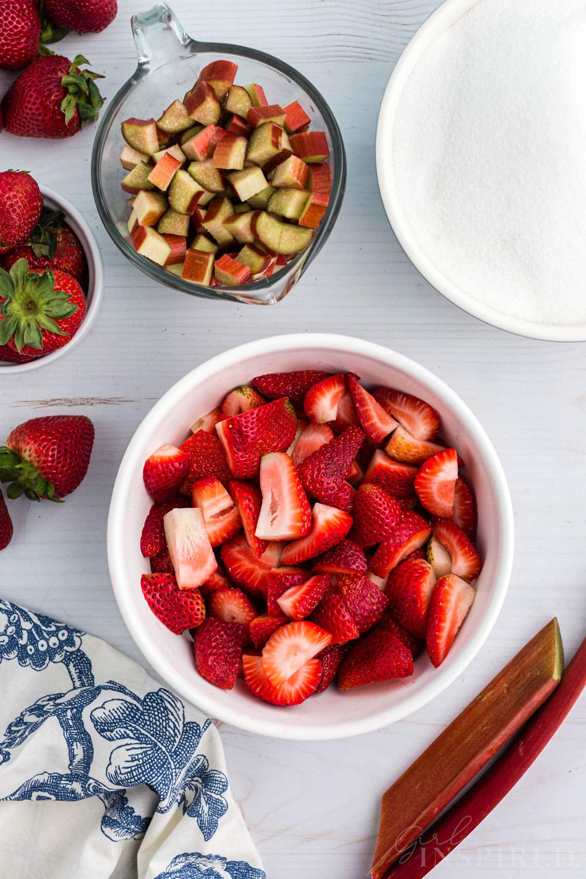 Sliced strawberry pieces and rhubarb pieces measured into bowls.