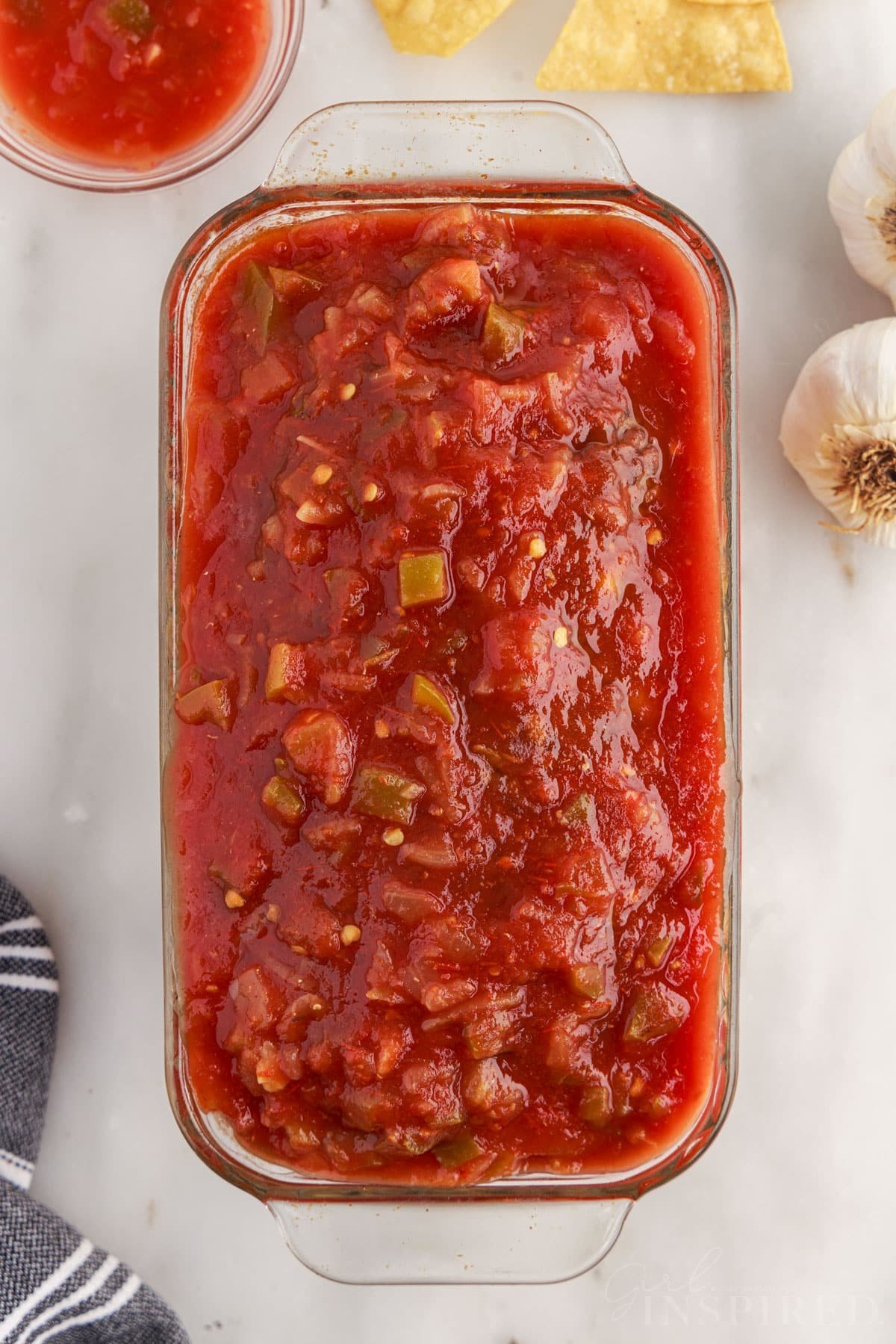 Meatloaf topped with salsa in a loaf pan.