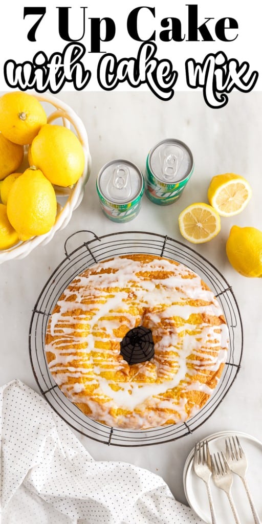 7 Up Cake with Cake Mix on a circular cooling rack with cans of 7 Up, some cutlery and lemons around it on a white kitchen counter top