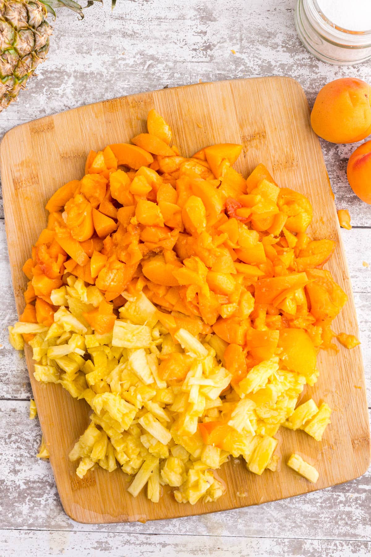 Chopped apricot and pineapple on a wooden kitchen board.