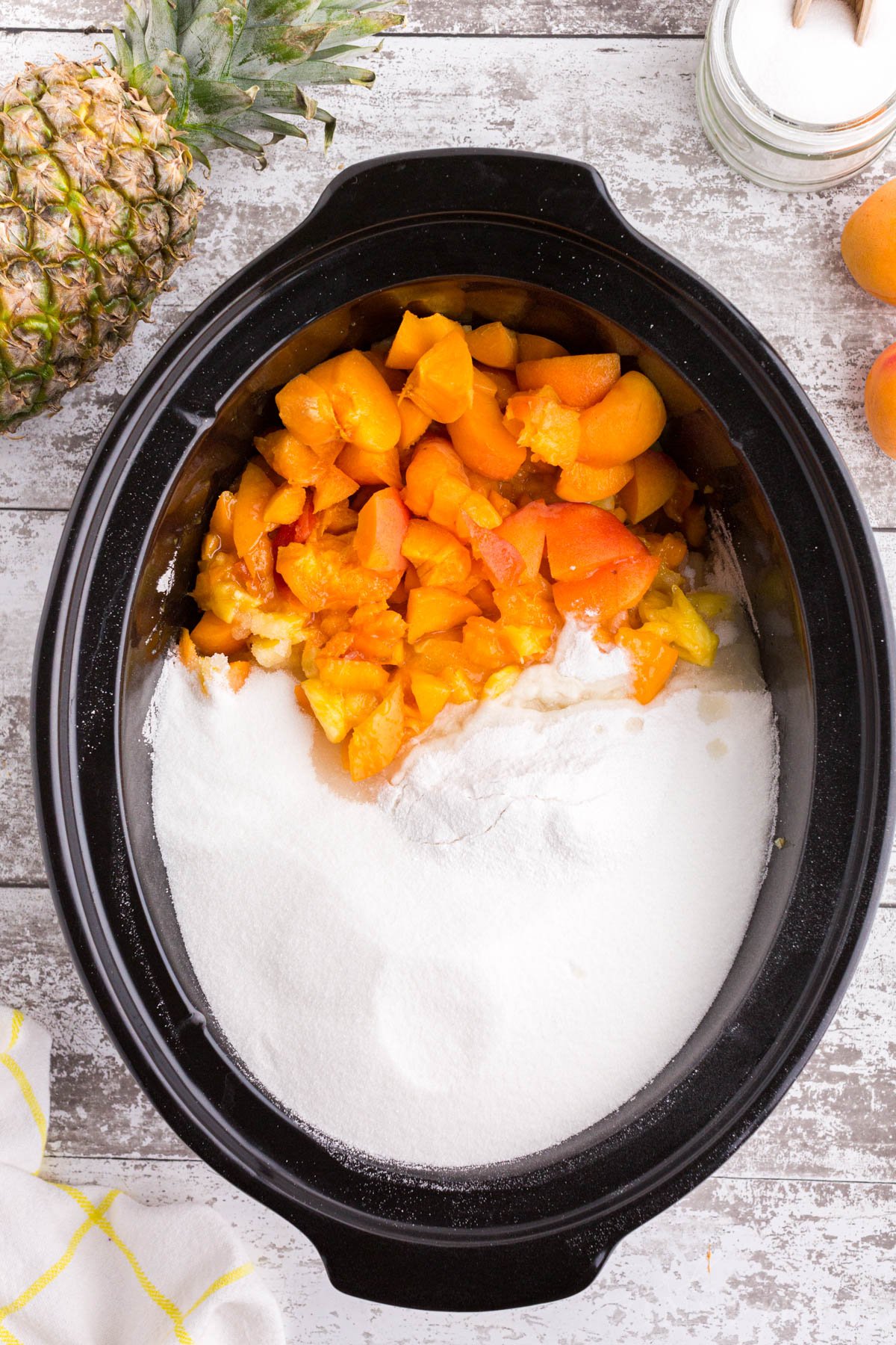 Freshly chopped apricots, pineapple, pectin, and sugar in a Crockpot.