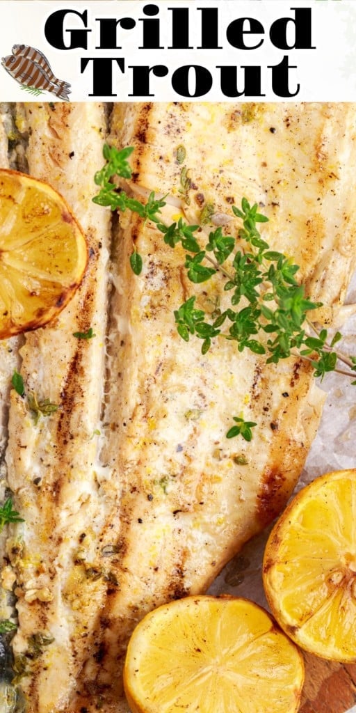 Close up of Grilled Trout on a wooden kitchen board with cut up lemons and sprigs of herbs scattered around