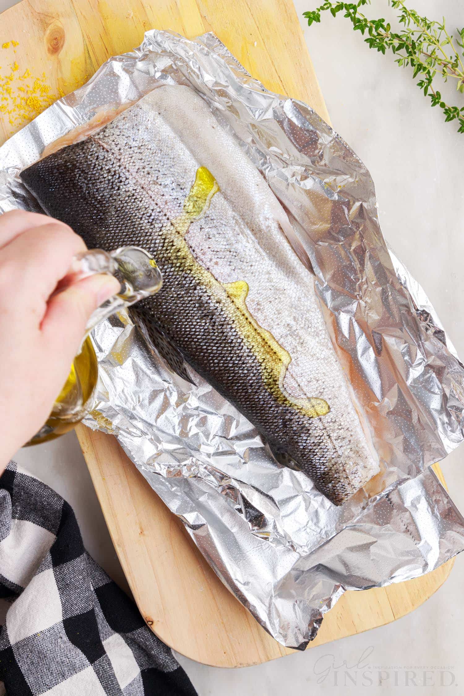 Oil being poured on trout in foil.