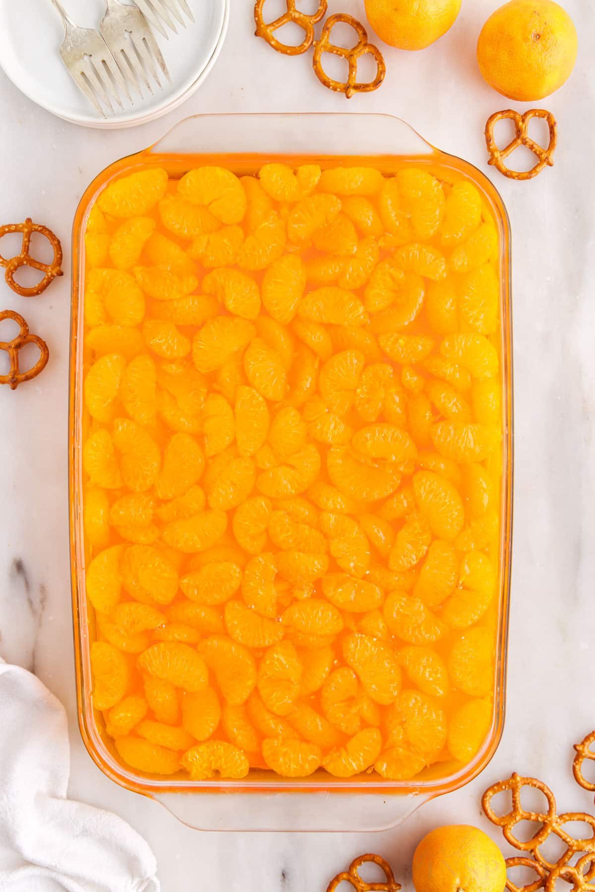 Orange gelatin mixture added to the top of the whipped topping in a 9x13 glass pan.