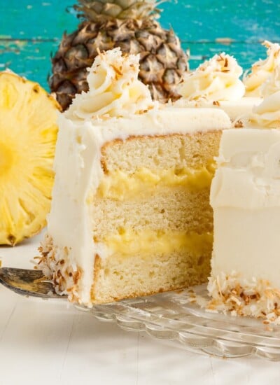 A slice being cut from the cake next to a pineapple.