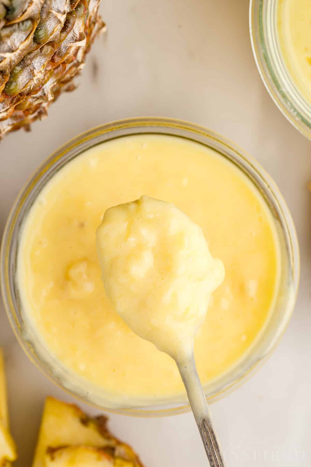 Pineapple Curd on a spoon over a dish of it.
