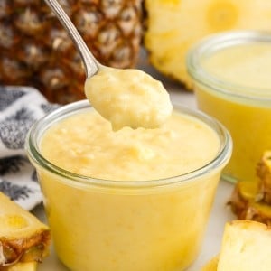 Pineapple Curd in a small glass dish and a spoonful lifted from it.