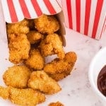 Popcorn chicken in a decorative paper bow with dipping sauce.