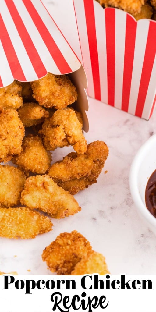 Popcorn chicken in decorative paper boxes, bowl of dipping sauce on the side on a white marble counter top