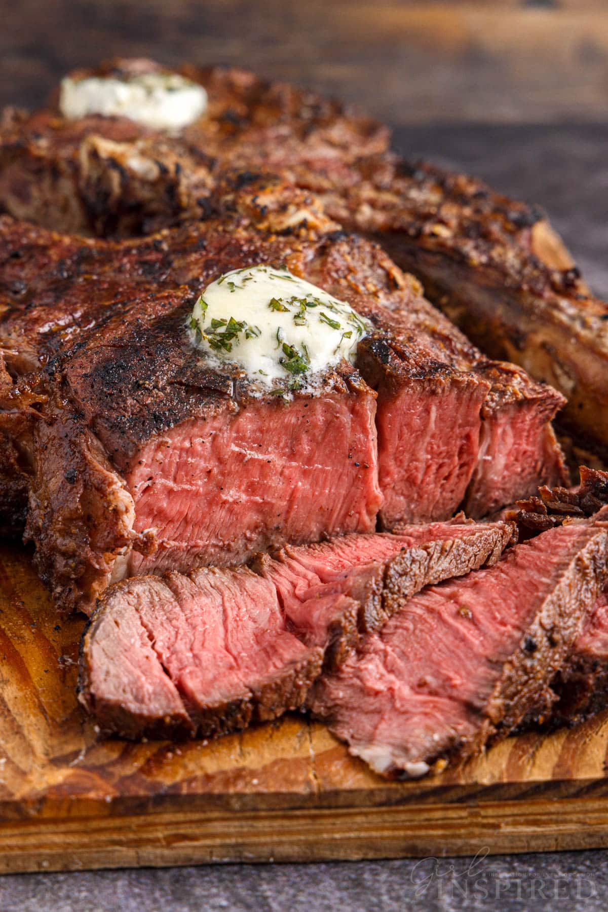 Sliced Tomahawk steak on a wooden kitchen board.