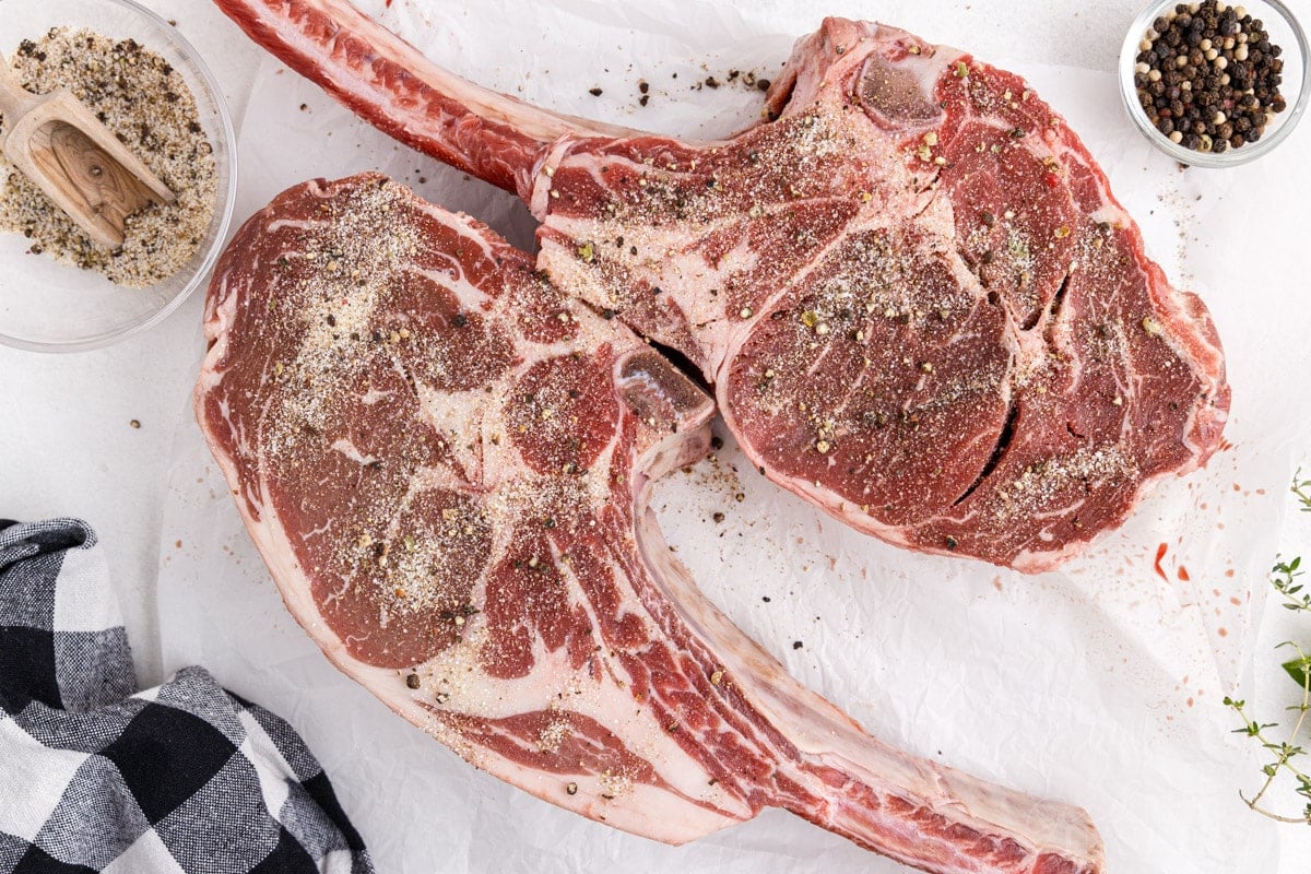 Two Tomahawk steaks with seasoning mixture rubbed into the meat.