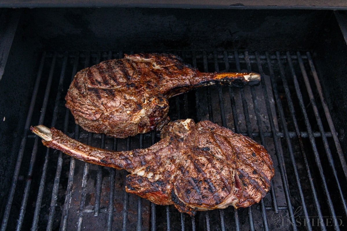 Two Tomahawk steaks on a hot grill.