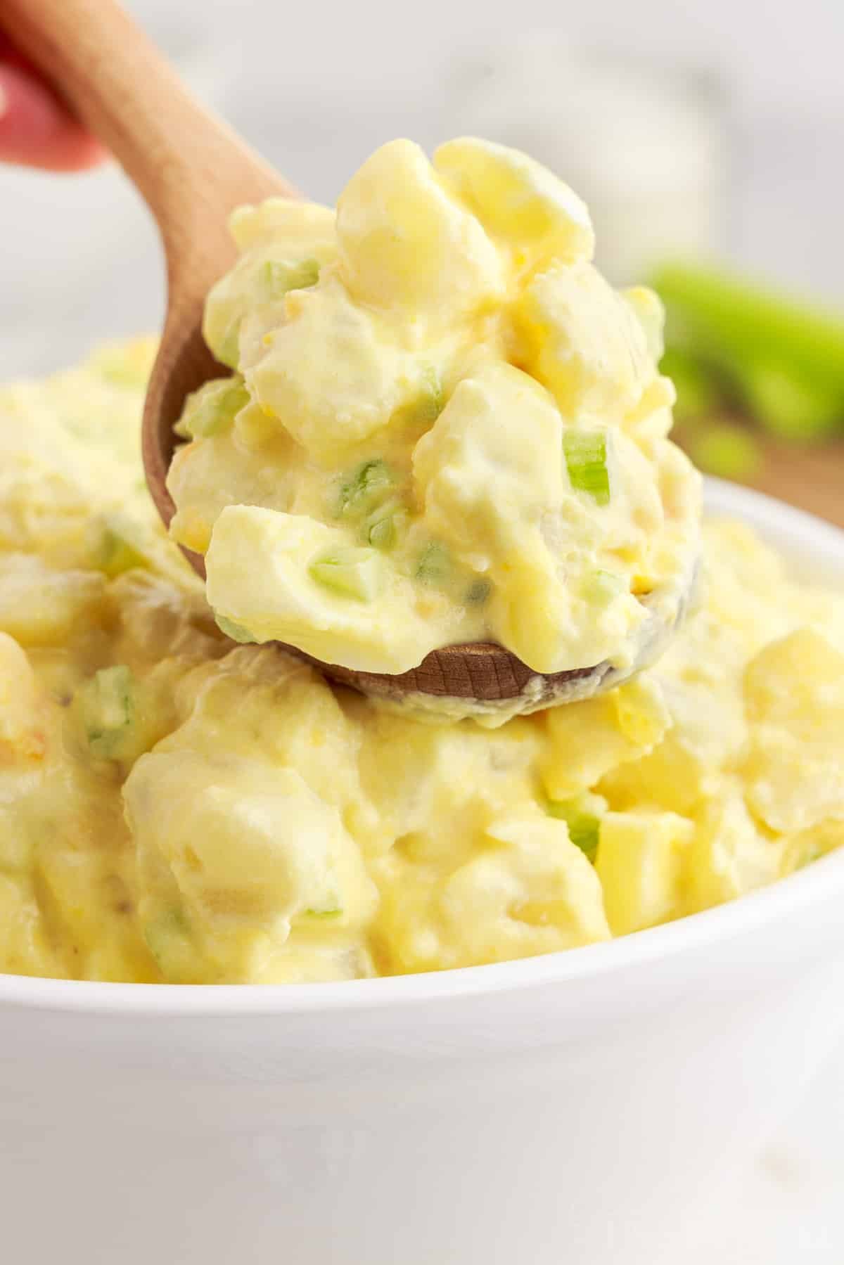 Amish Potato Salad on a spoon over a bowl.