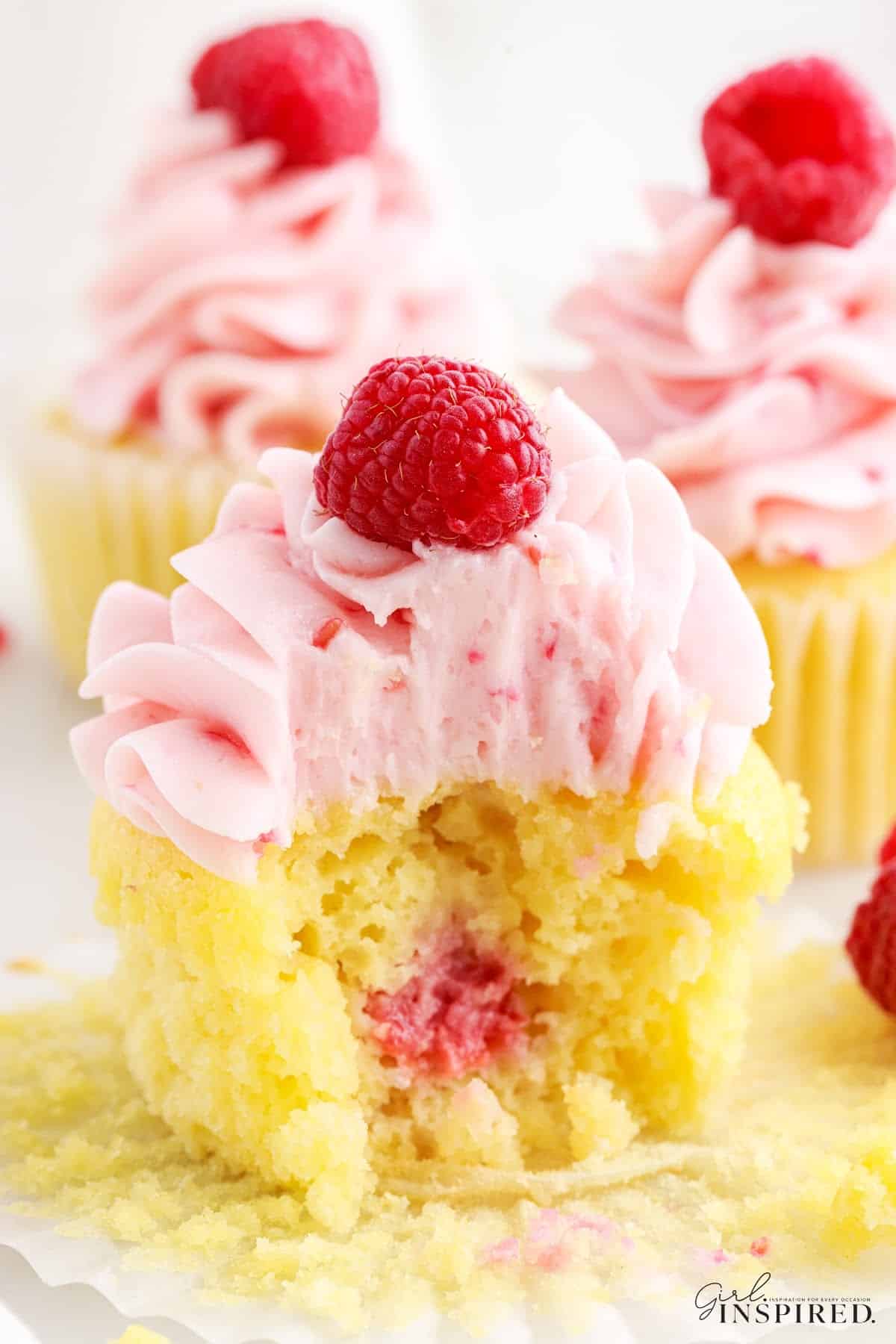 Close up of Raspberry Cupcakes with a bite taken from the front one.