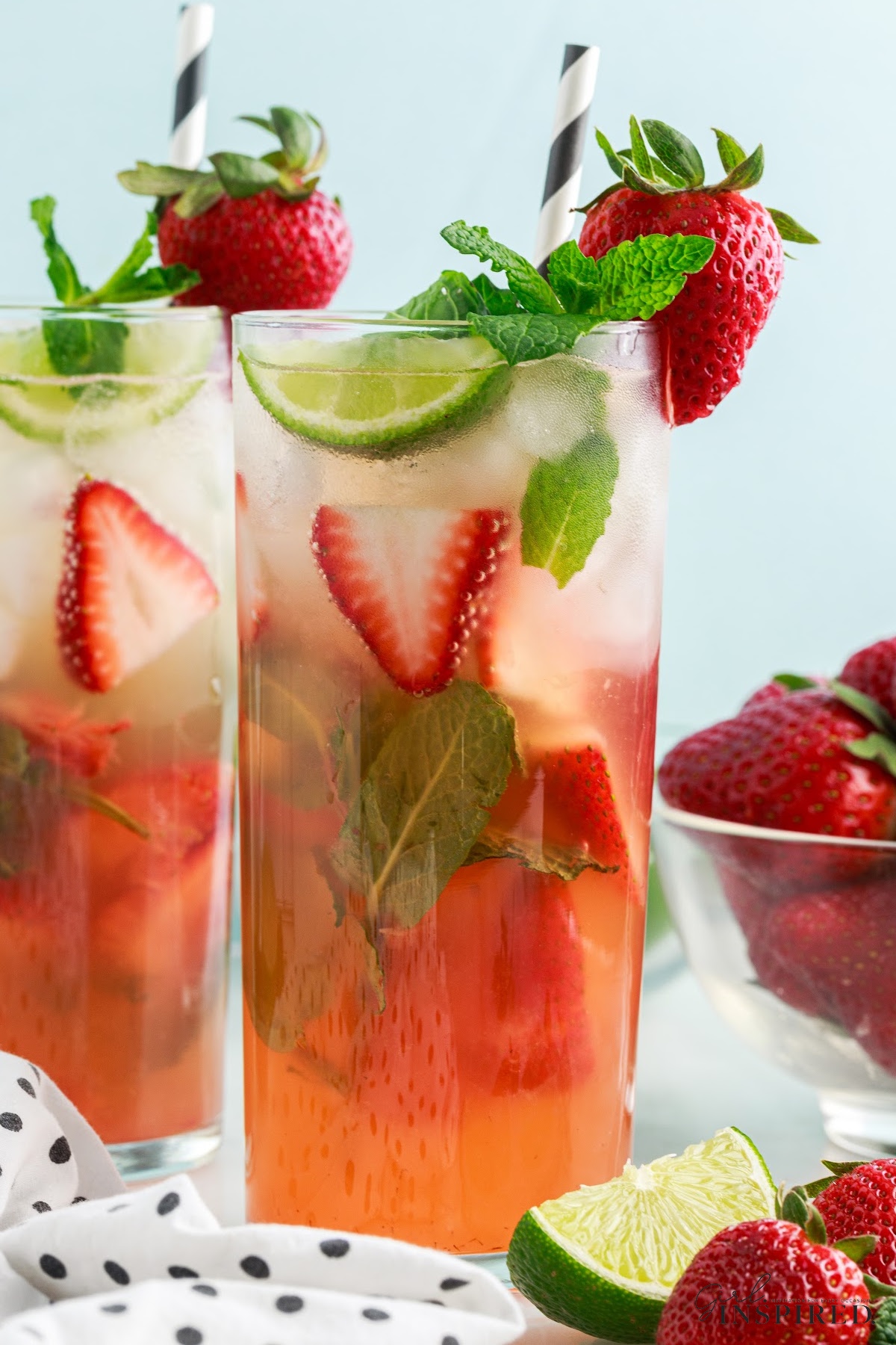 Strawberry Mojitos garnished with mint, lime, and strawberries.