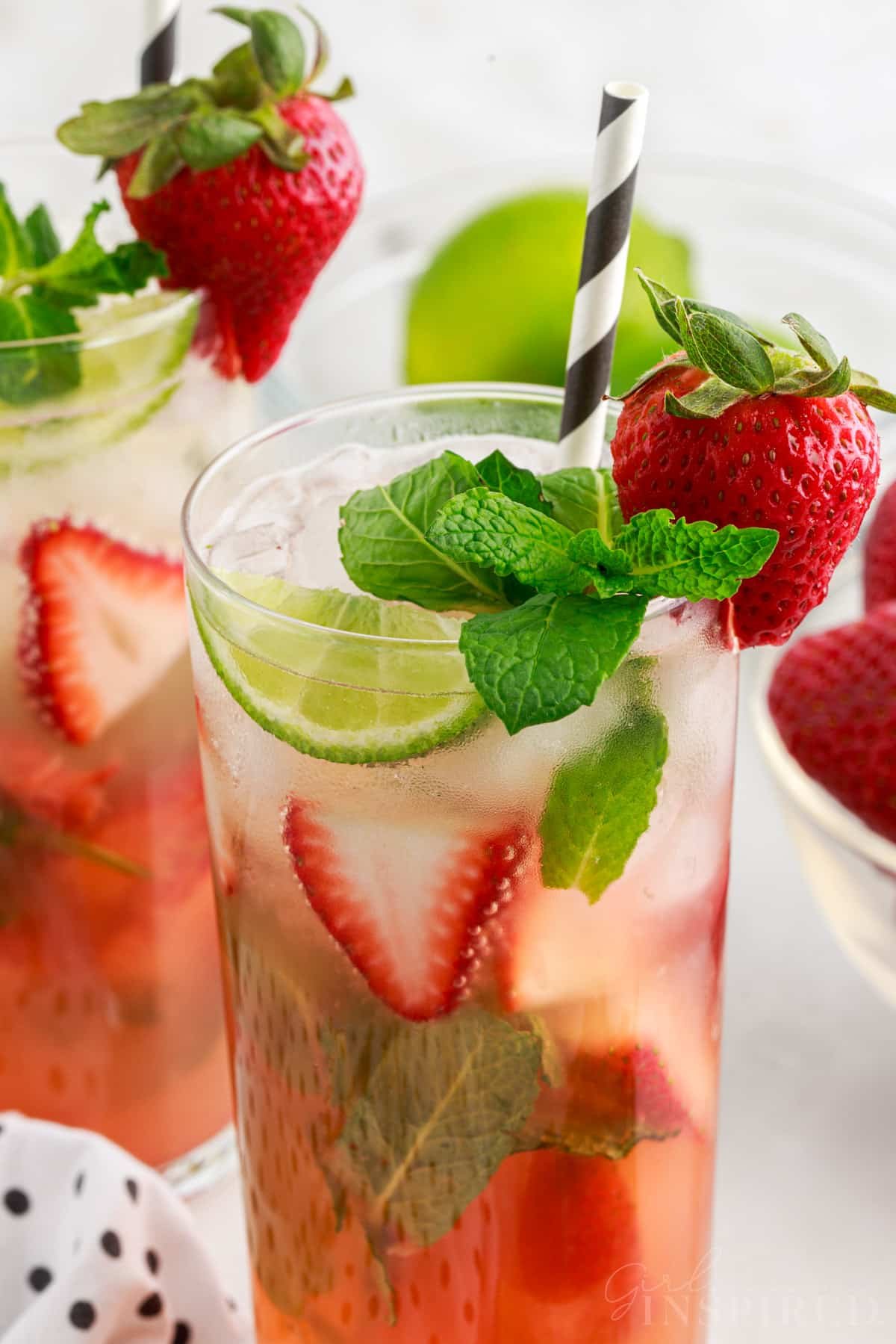 Two Strawberry Mojito in tall glasses garnished with mint and strawberries.