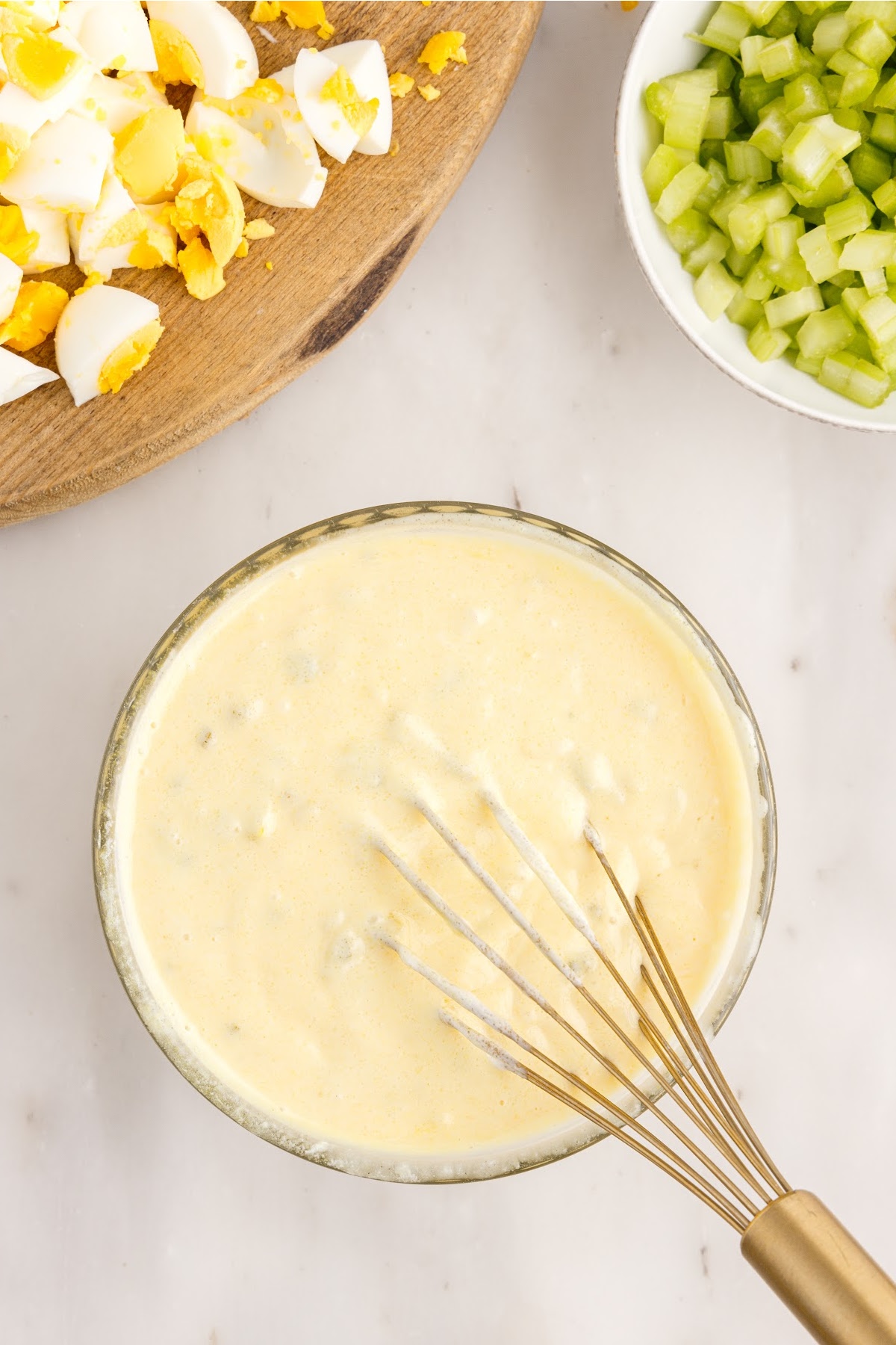 Amish Macaroni Salad dressing in a dish with a whisk inserted.