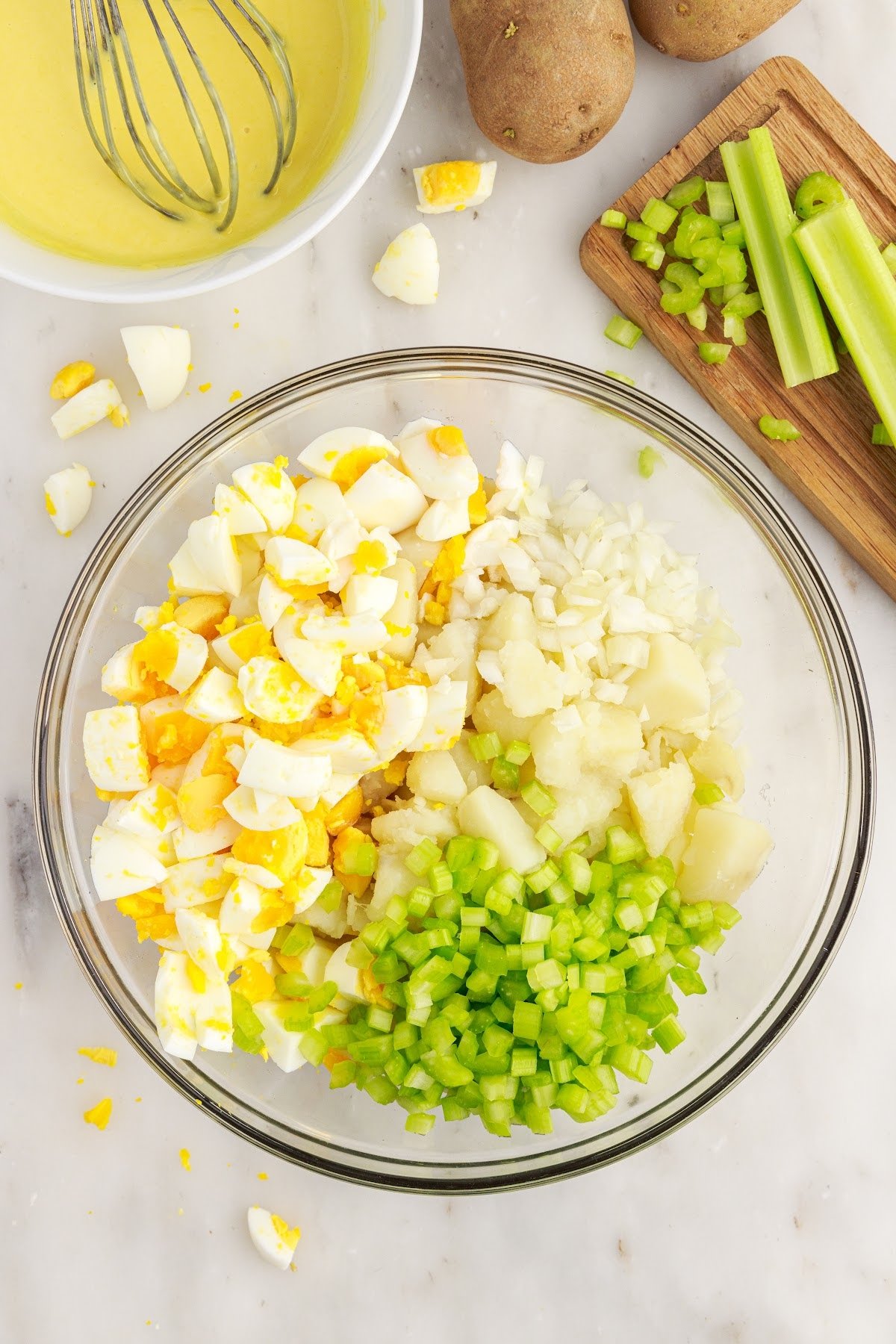Celery, potatoes, eggs, and onion in a serving bowl.