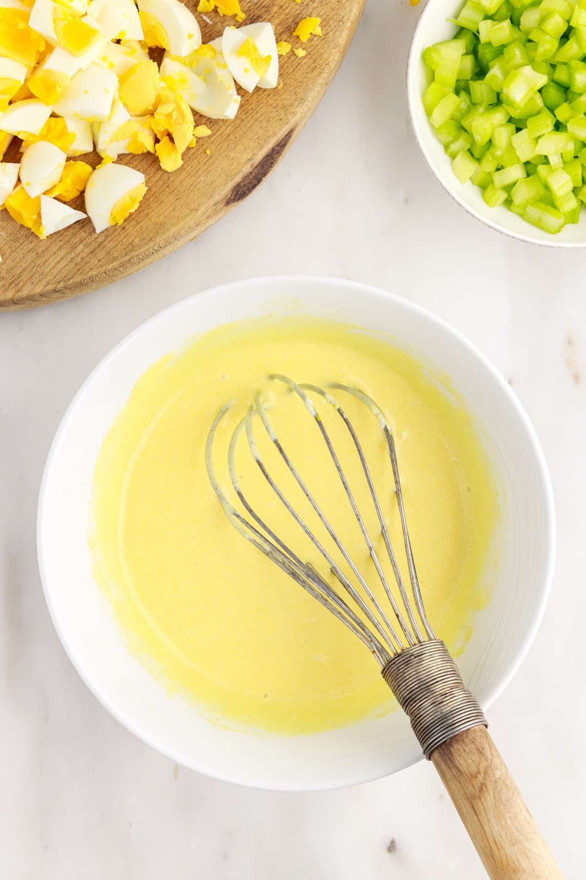 Amish Potato Salad dressing in a small dish with a whisk.