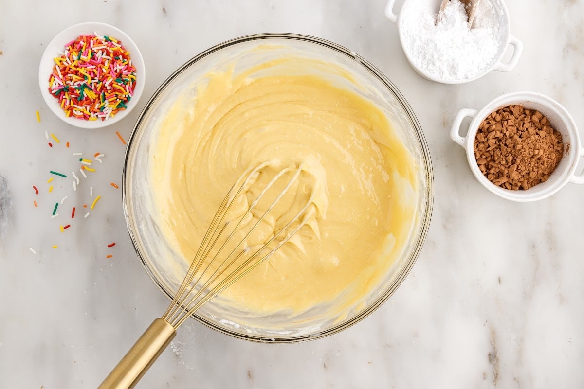 Cake Mix Donuts batter in a mixing bowl with a whisk.