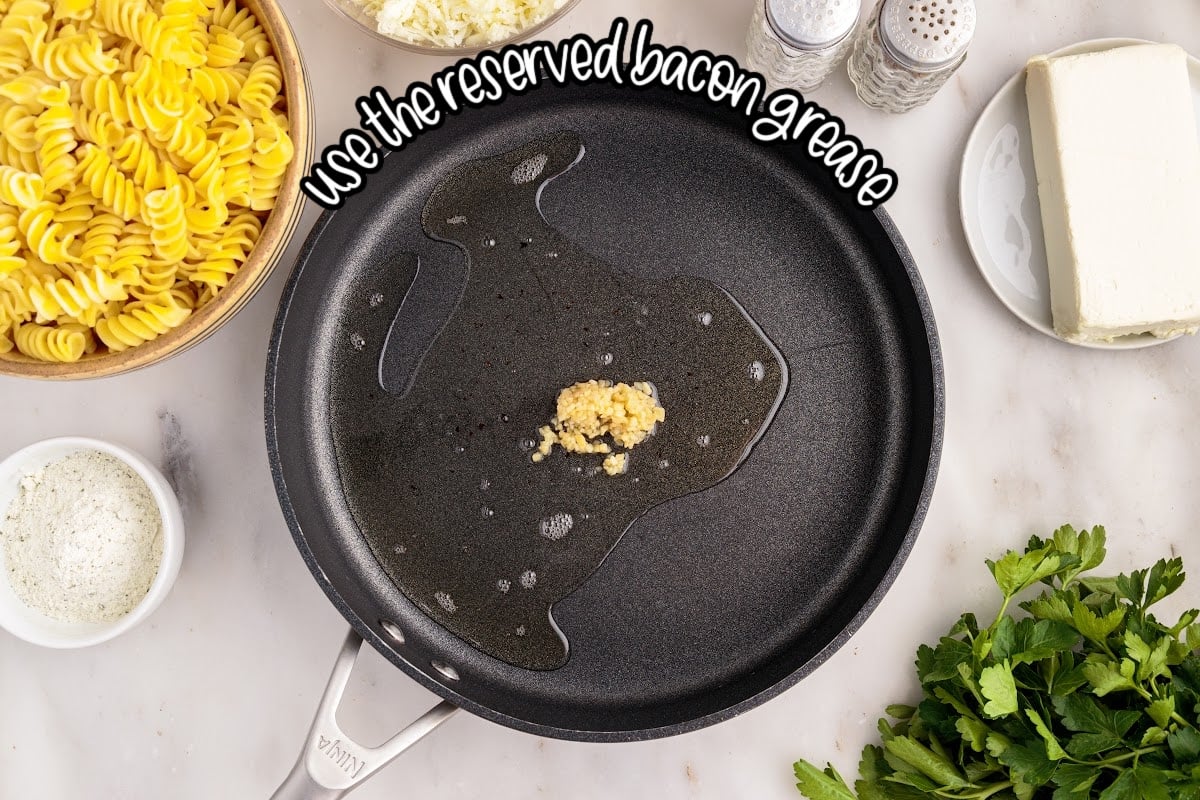 Skillet with bacon grease and garlic with text overlay.