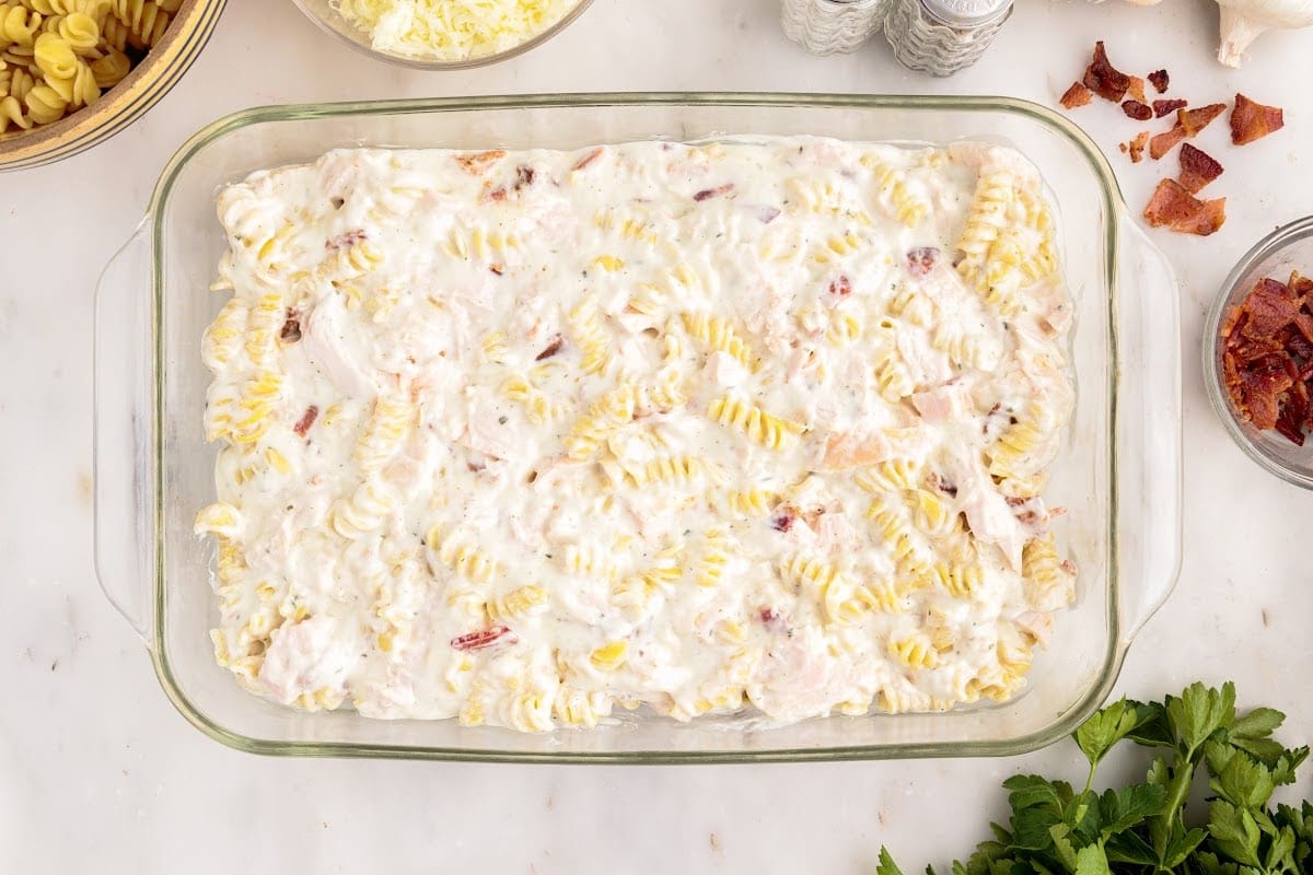 Pasta and sauce mixture added to a 9x13 glass dish.