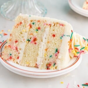 A slice of Funfetti Cake laying on its side on a plate.