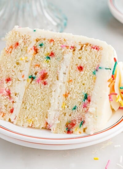 A slice of Funfetti Cake laying on its side on a plate.