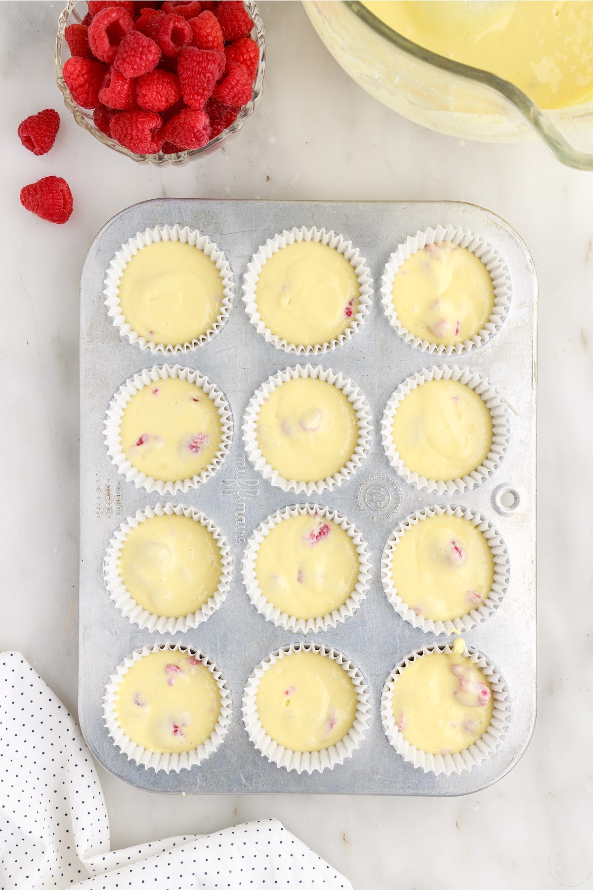 Overhead view of a muffin tin lined and filled with Raspberry Cupcake batter.